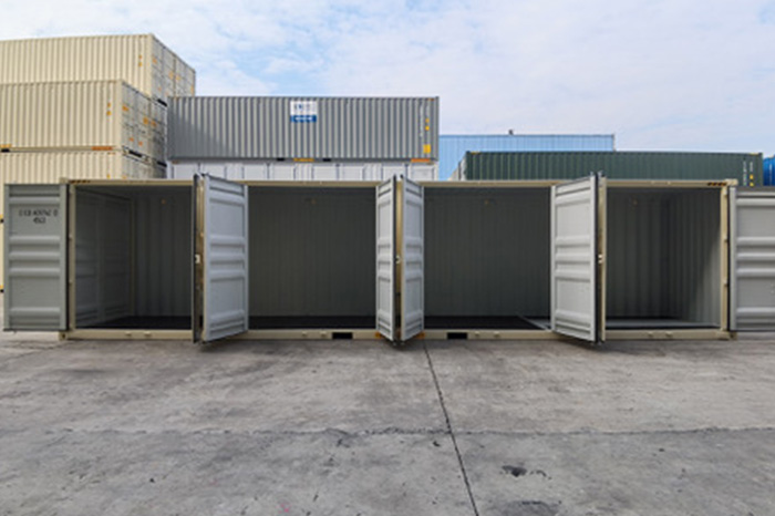 Four open shipping crates with other stacked behind